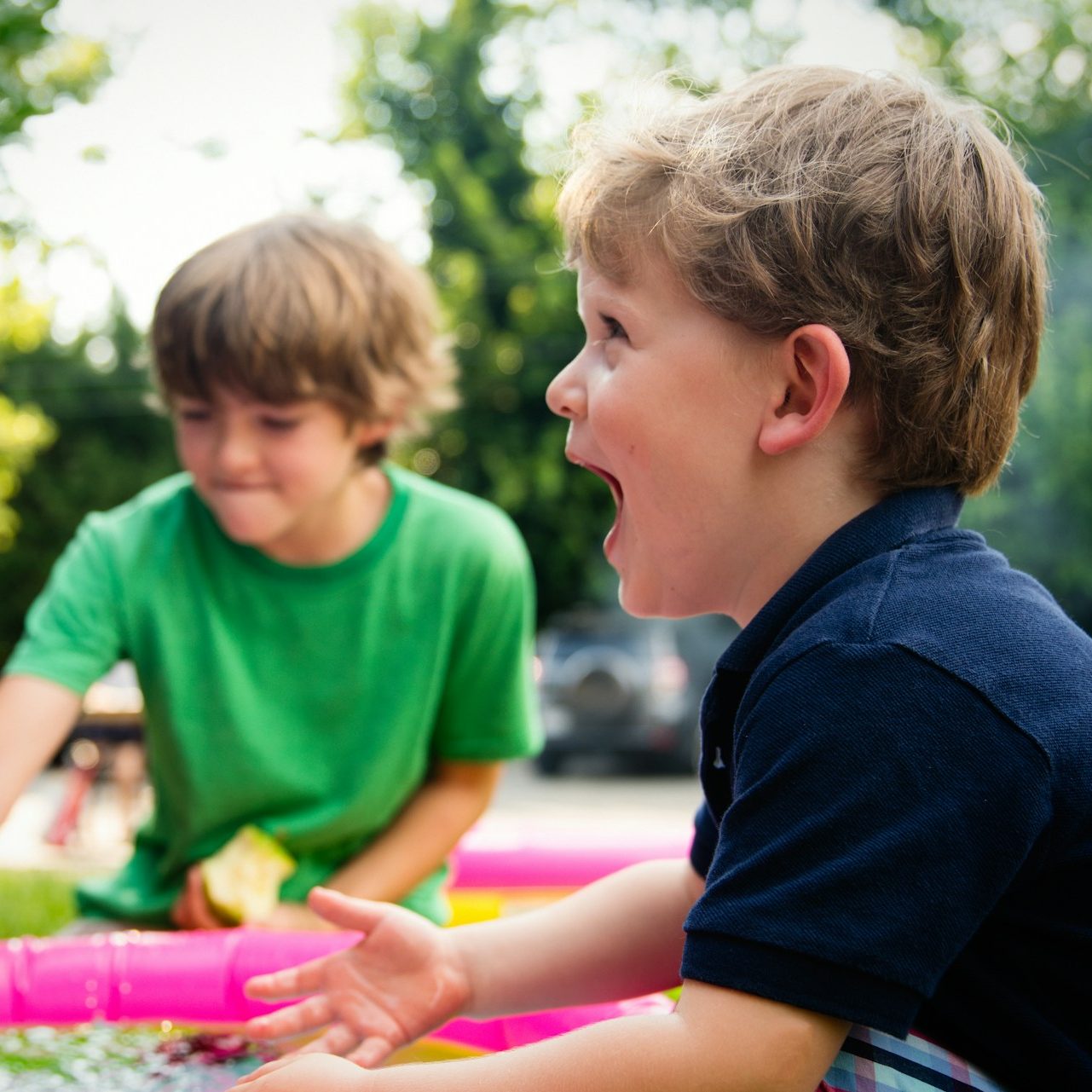 boy in blue shirt screaming near boy in green crew-neck shirt